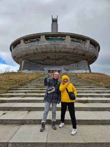 Winter visitors at Buzludzha Monument main entrance wearing warm clothing during cold season tour